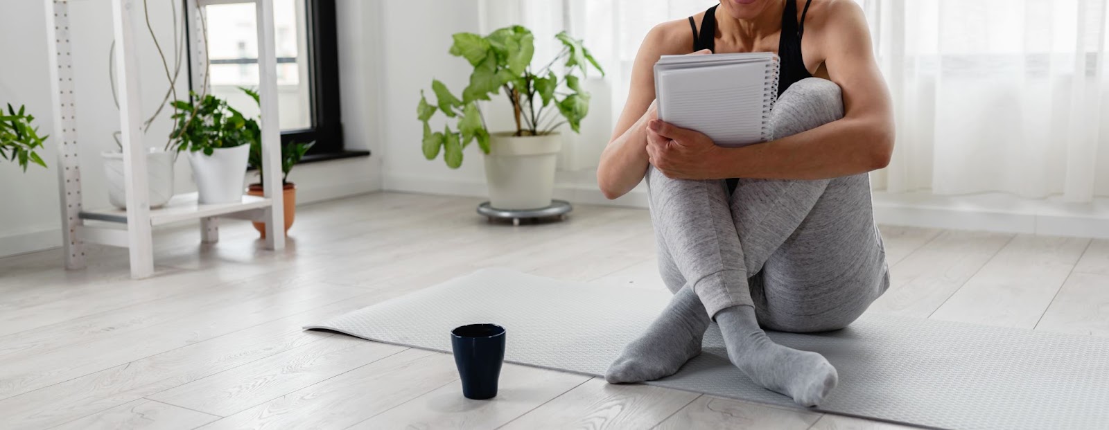 Fit woman, sitting on a yoga mat, planning her workout schedule for the week.