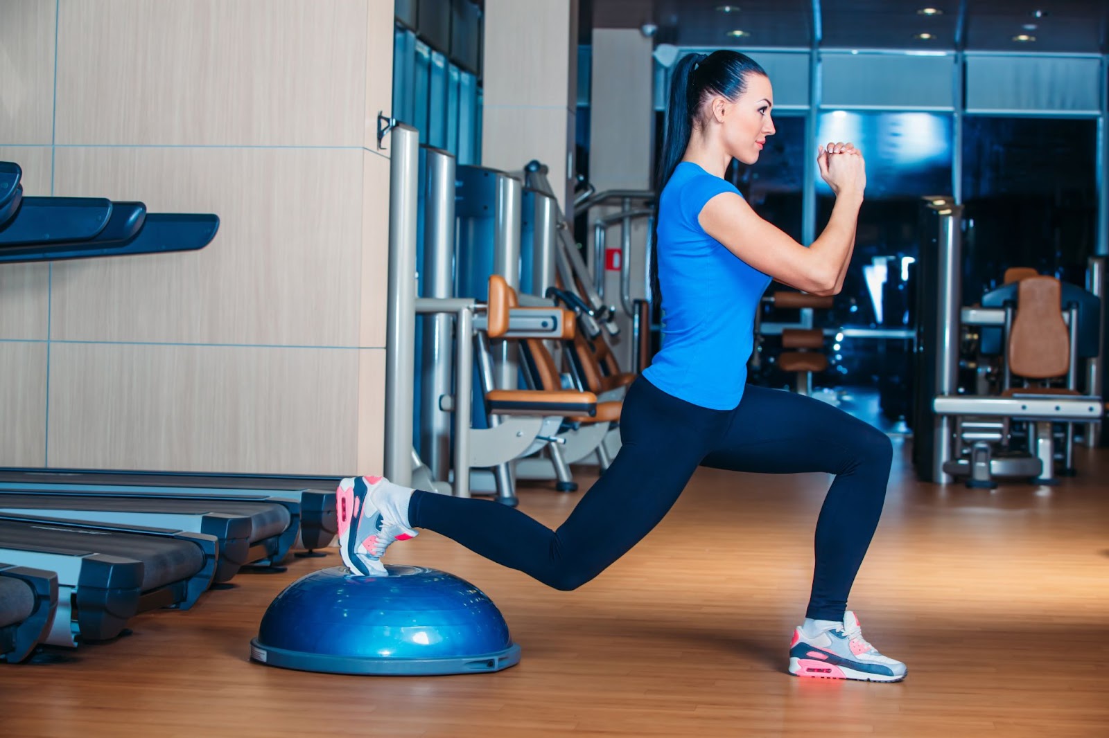 Fit woman going down in a lunge position on her BOSU ball.