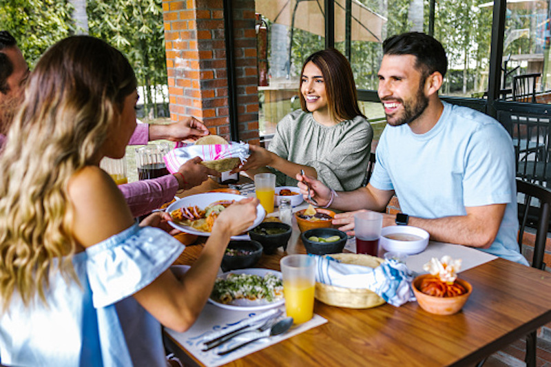 Attractive young friends sitting down to eat a healthy keto lunch together