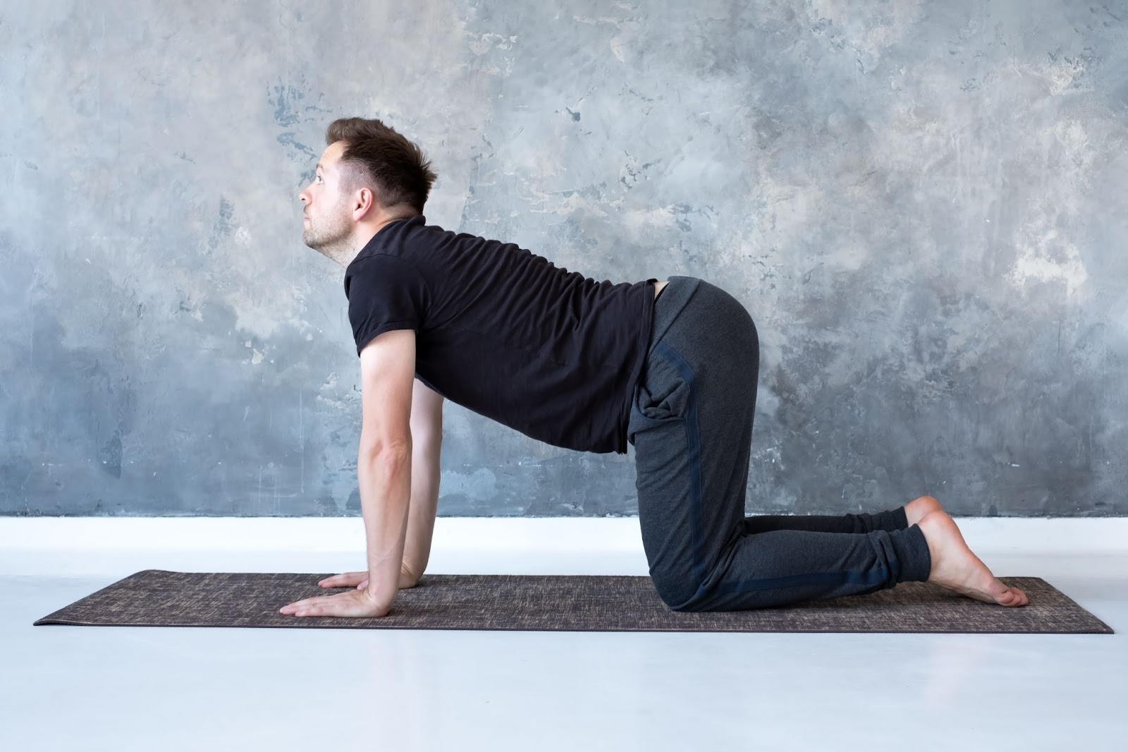 Man in black shirt performing a cat cow exercise