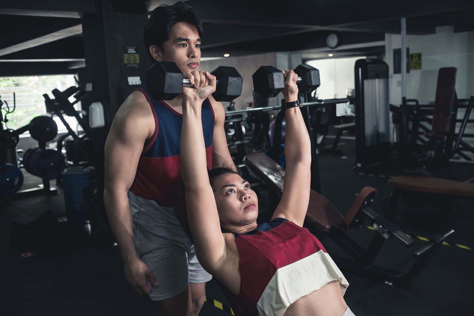 Man spotting a woman doing an incline shoulder press