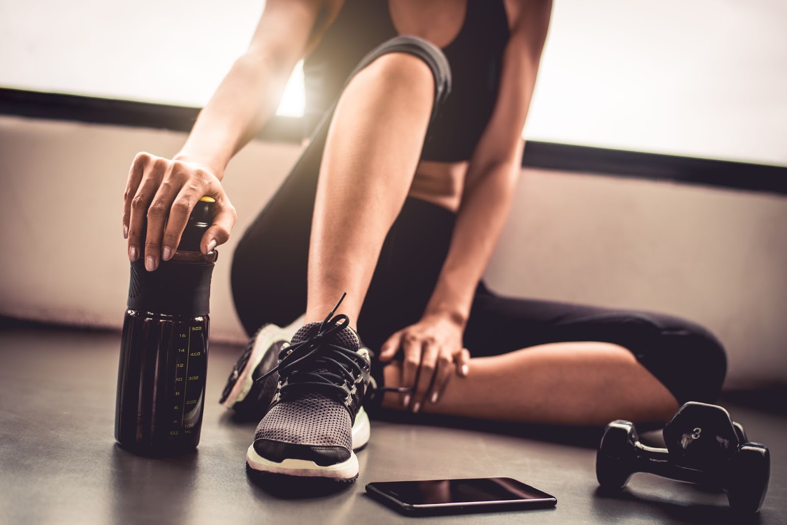 Woman in a gym holding an expensive metal water bottle