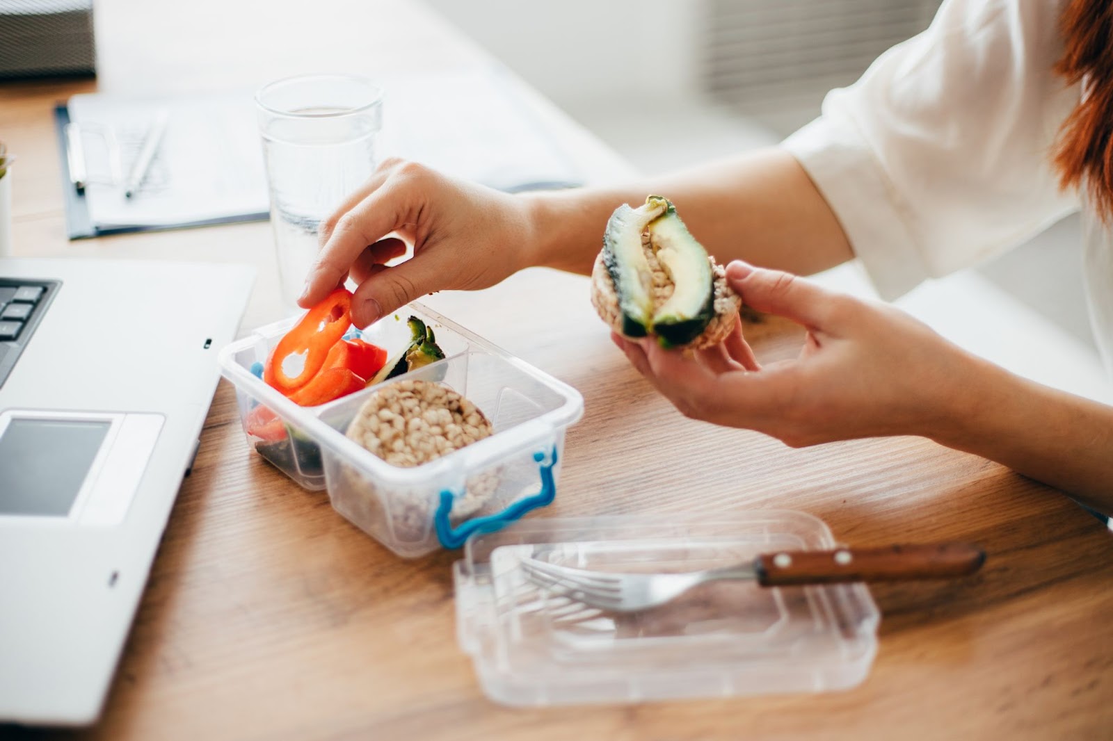 Person eating healthy rice cakes and avocado at work