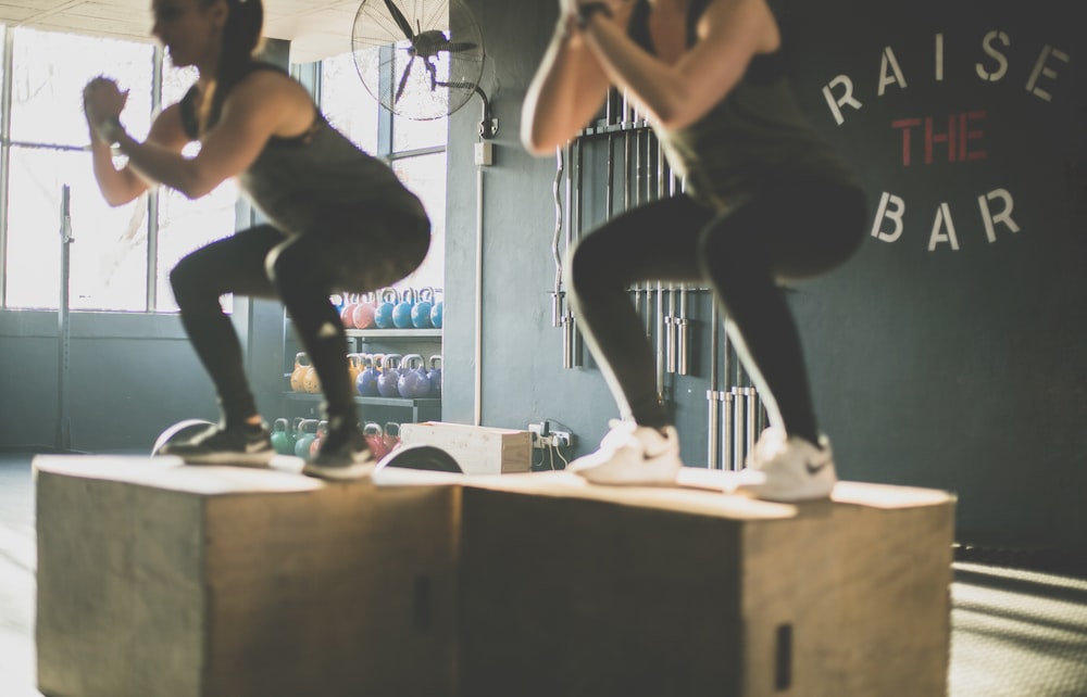 fit couple performing box jumps in a gym