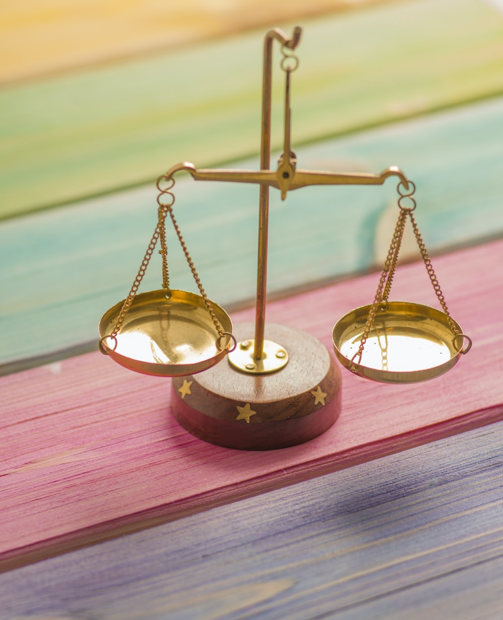 gold balancing scale on colorful background