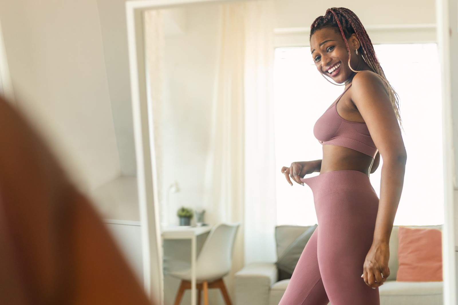 Attractive young woman checking her fitness progress in the mirror