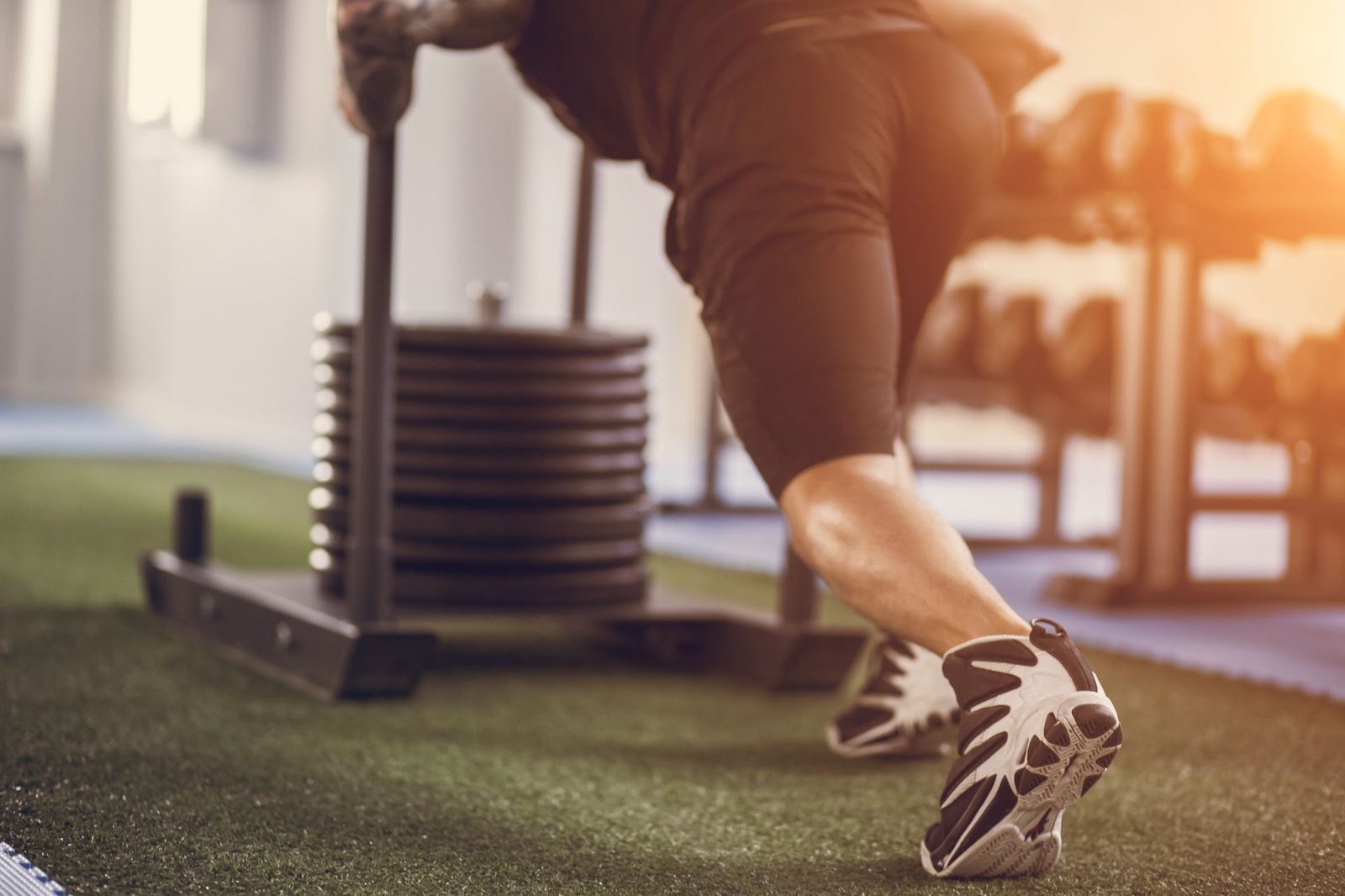 Man pushing the Prowler Sled across an astroturf floor in a gym