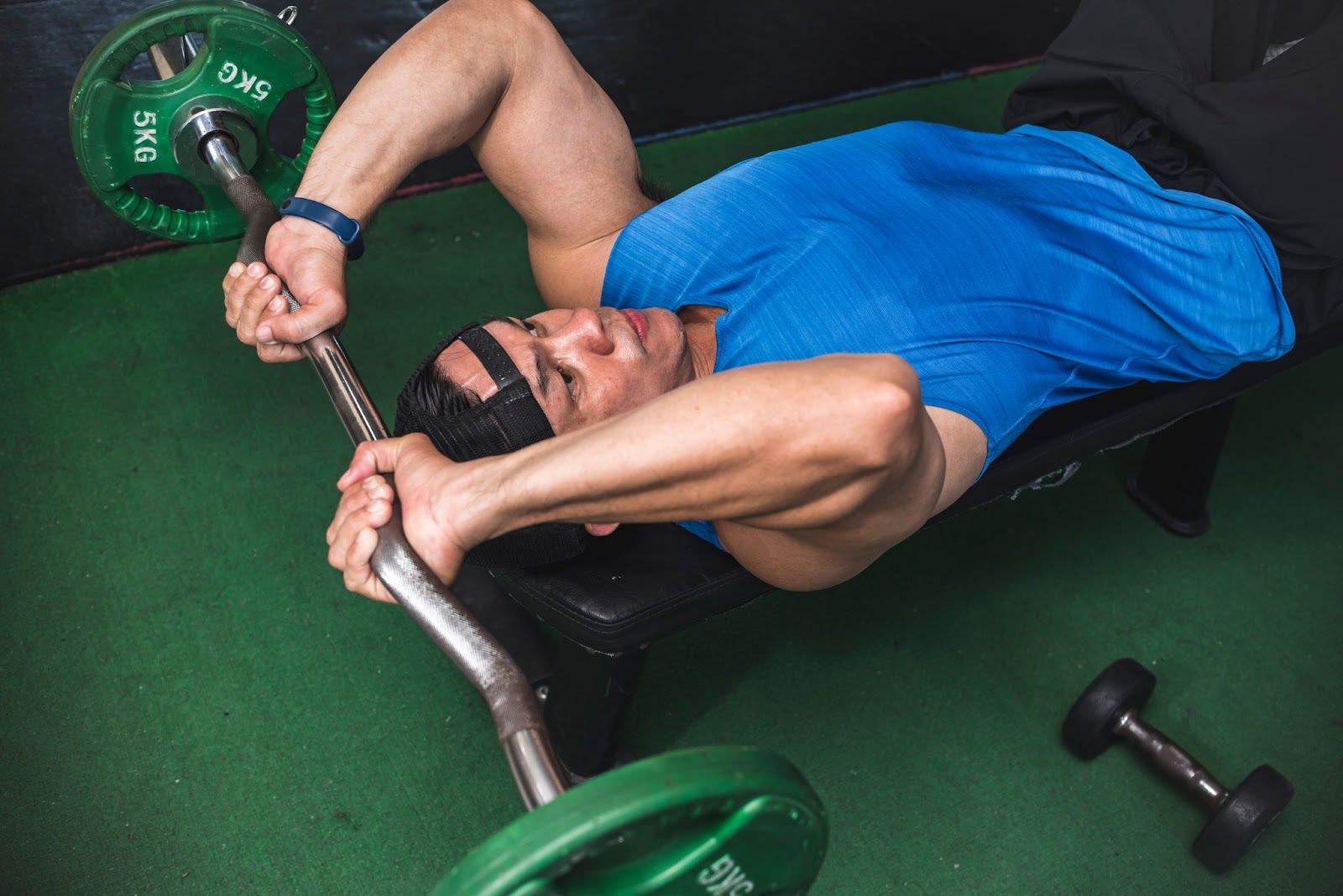 Fit man wearing a blue tank top performing skull crusher tricep exercises