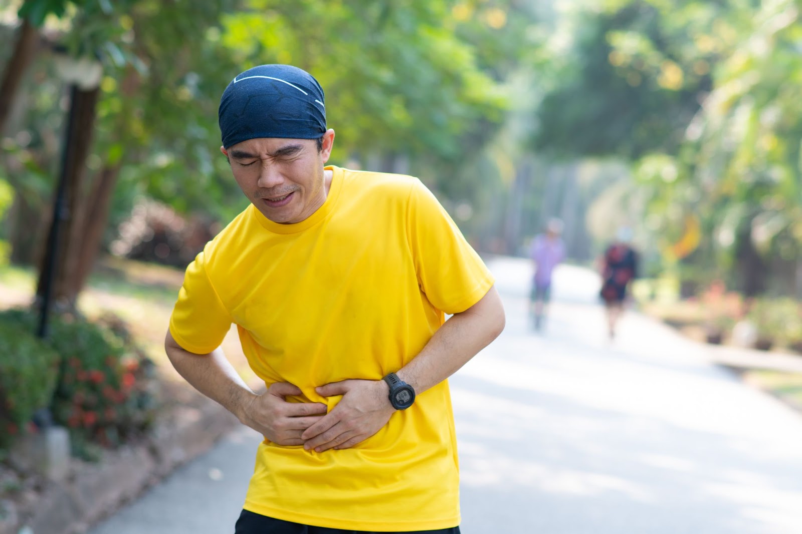 Man in a yellow shirt grasping his side while running