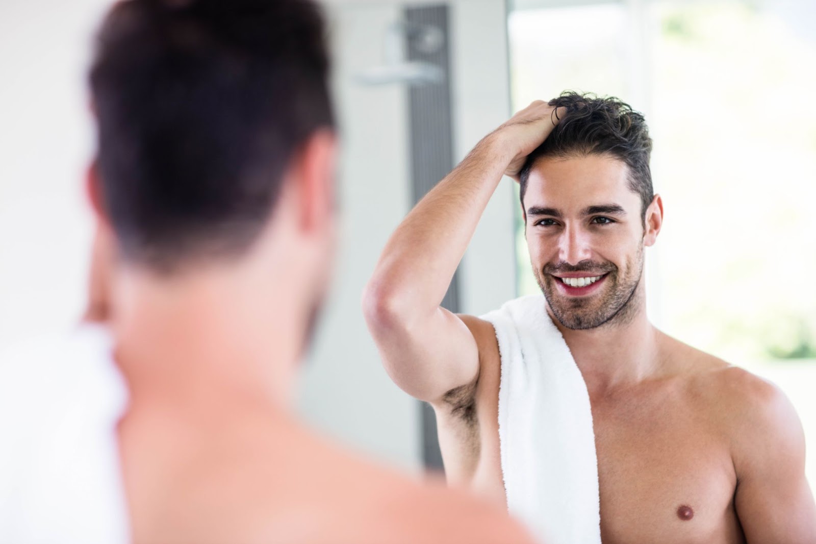 Handsome man looking in the mirror and smiling