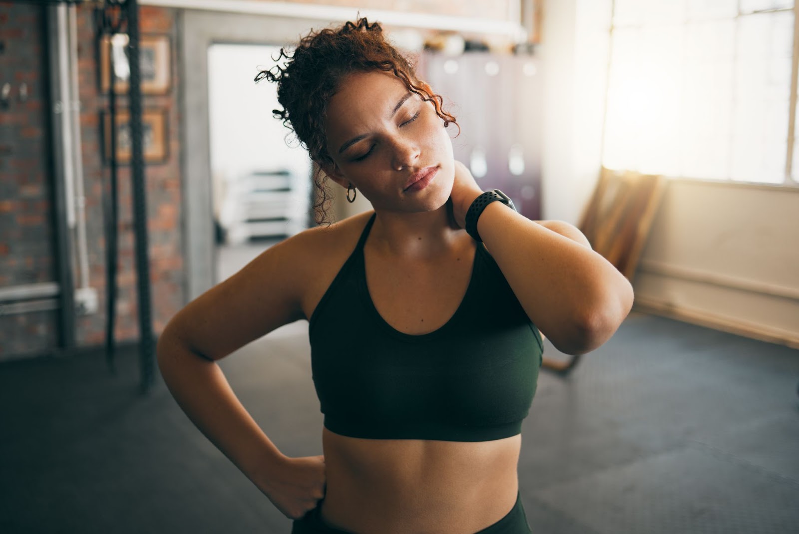 Sore woman holding her neck at the gym