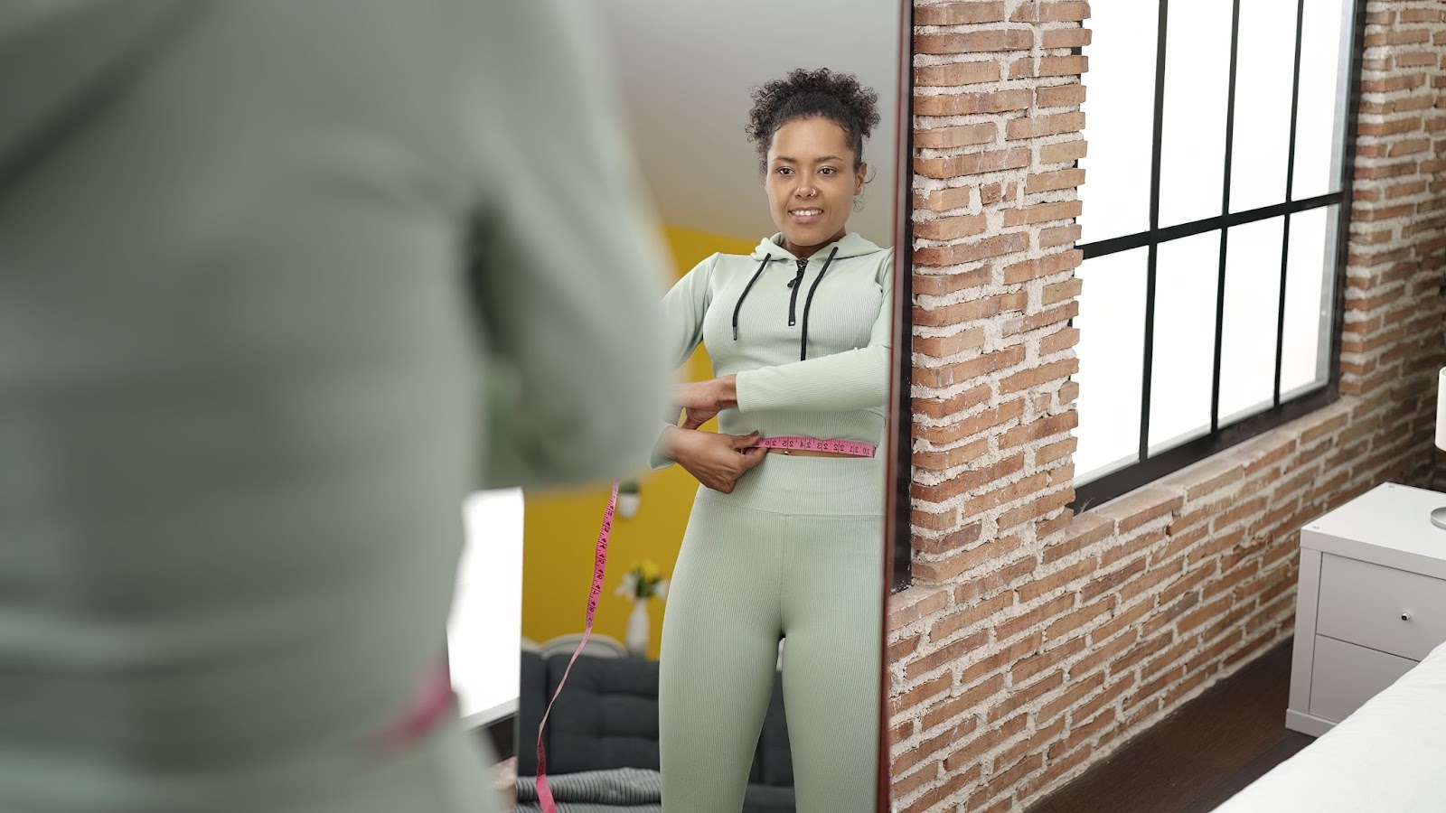 Fit, African American woman looking at herself in the mirror