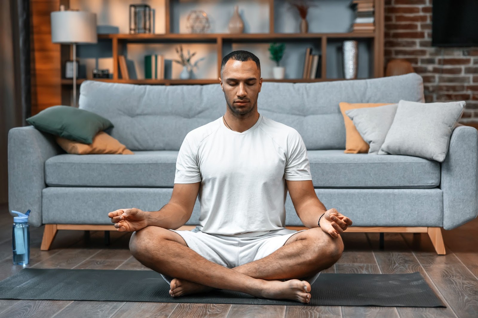 Older man meditating at home, sitting on the floor