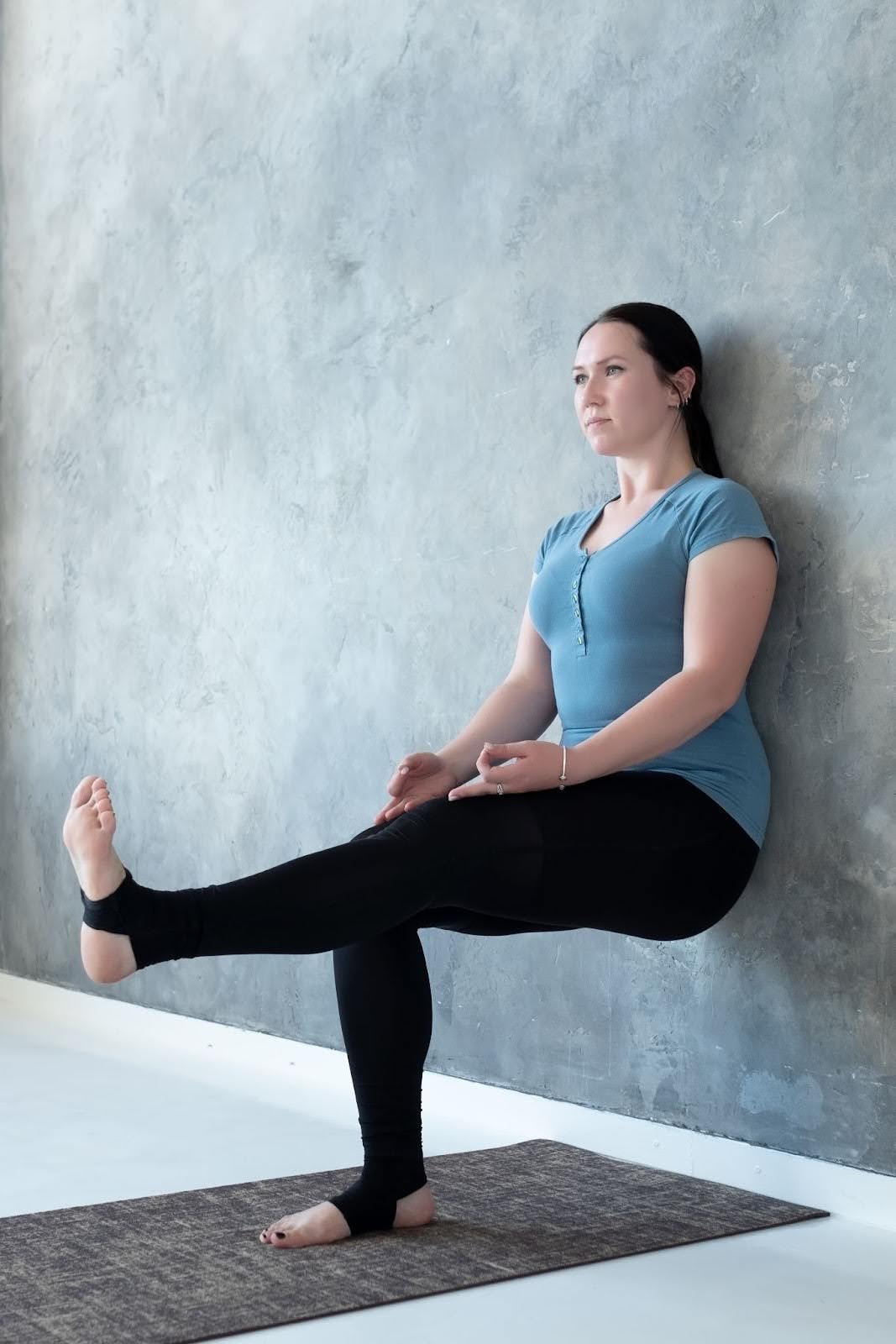 Blonde woman performing wall Pilates movements in a gym