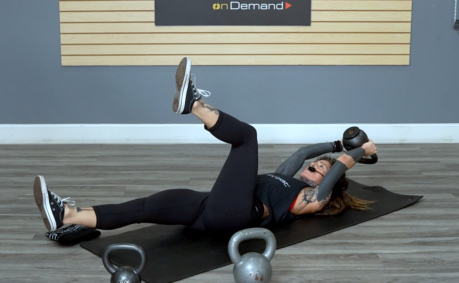 Fitness trainer performing a kettlebell dead bug exercise