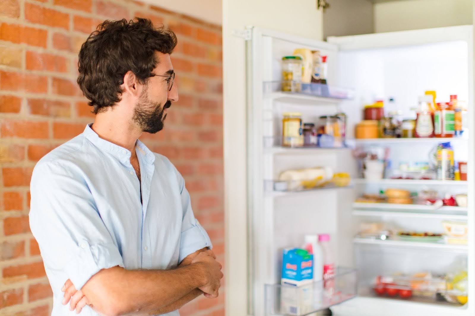Man standing in front of a refrigerator pondering his next meal