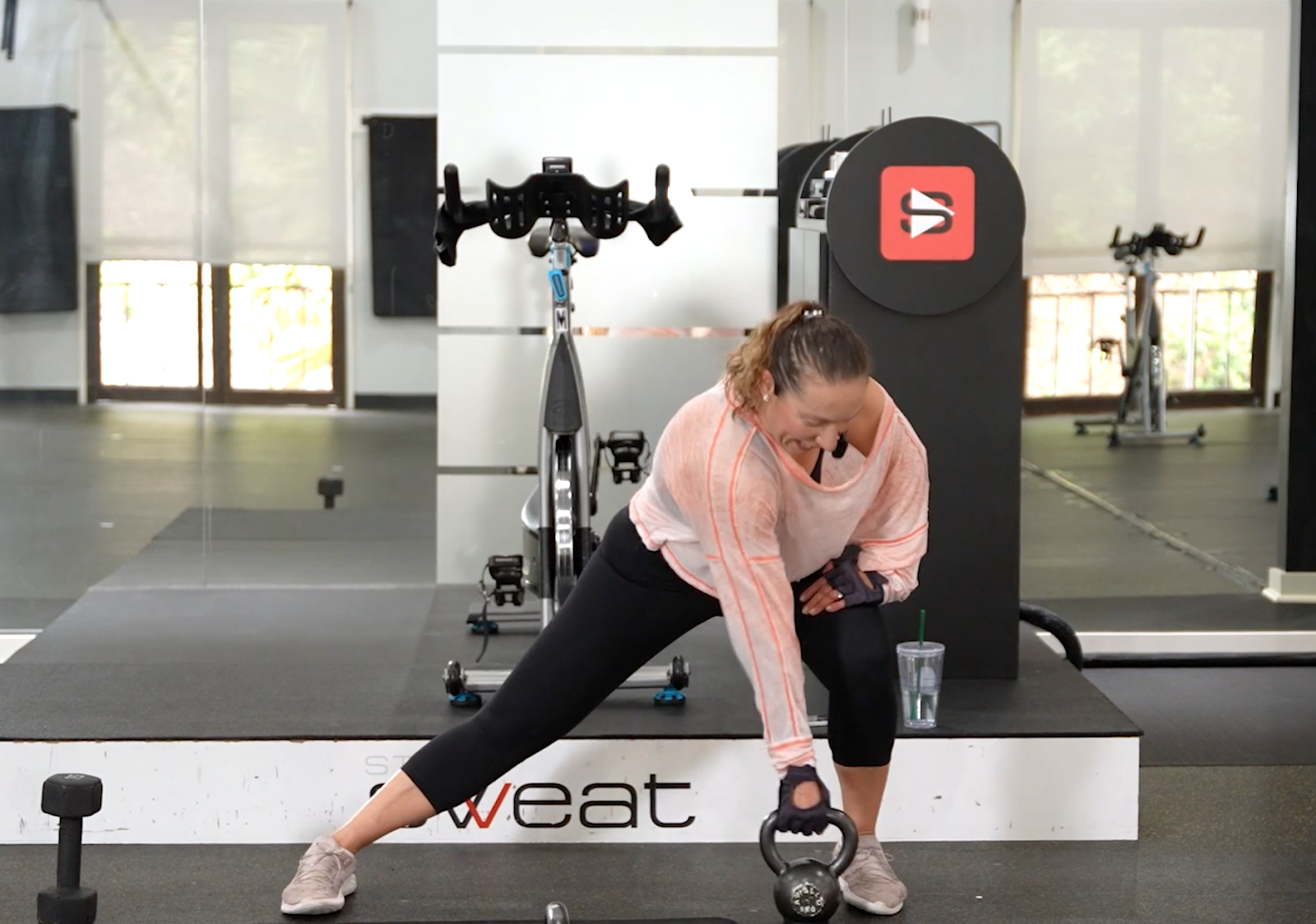 Studio SWEAT onDemand trainer performing a kettlebell lateral lunge