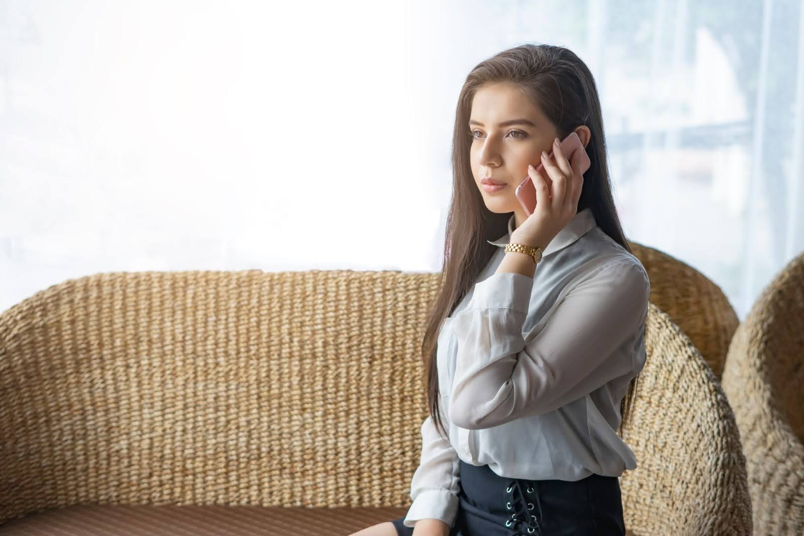 Woman sitting on couch with perfect posture, talking on the phone