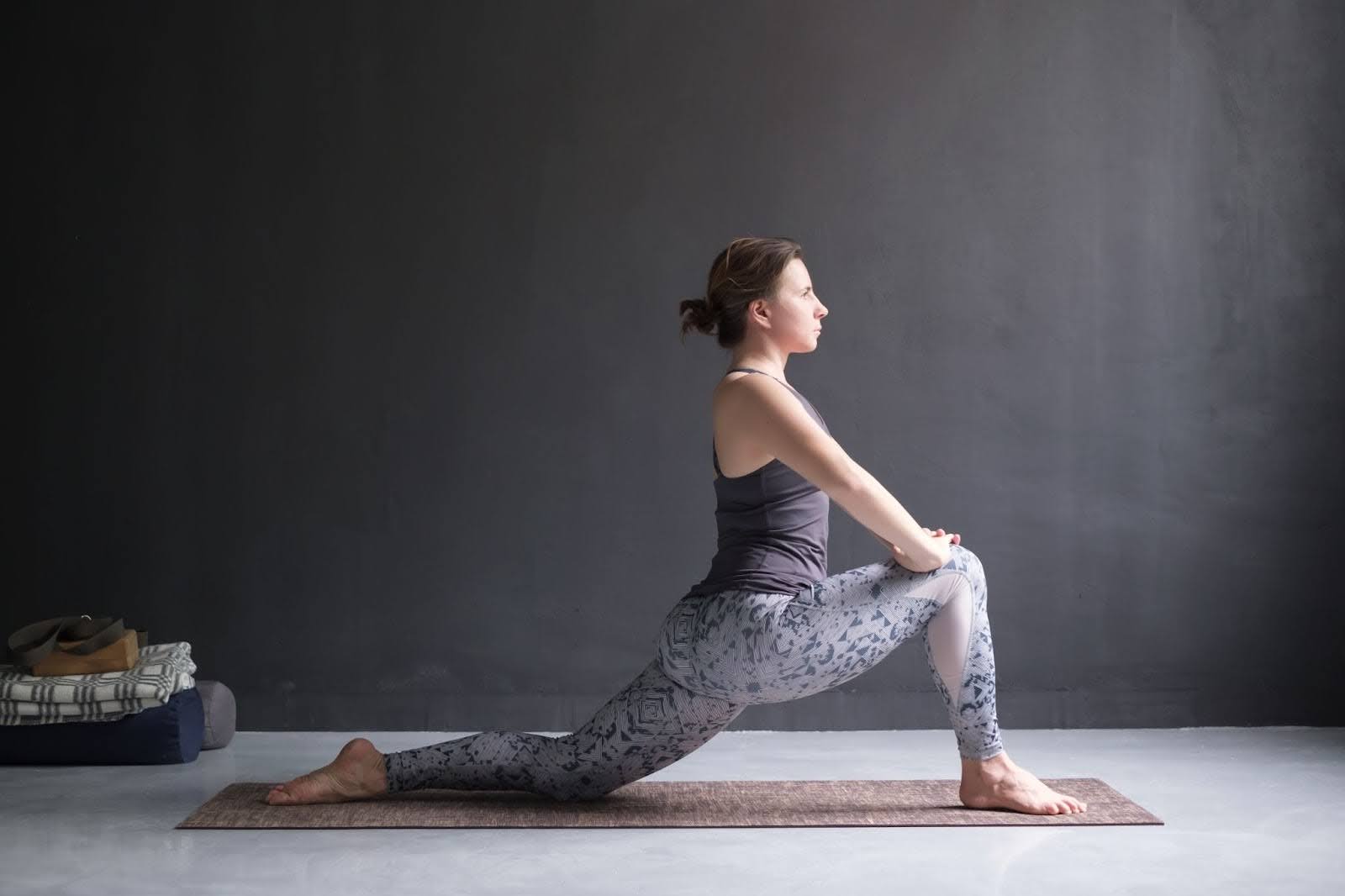 Woman in exercise gear performing a kneeling lunge stretch