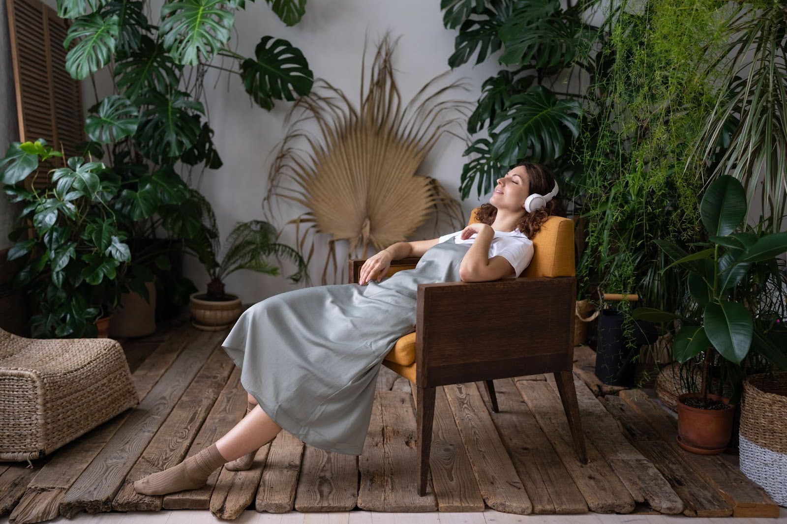 Woman resting at home in a chair, listening to music through headphones
