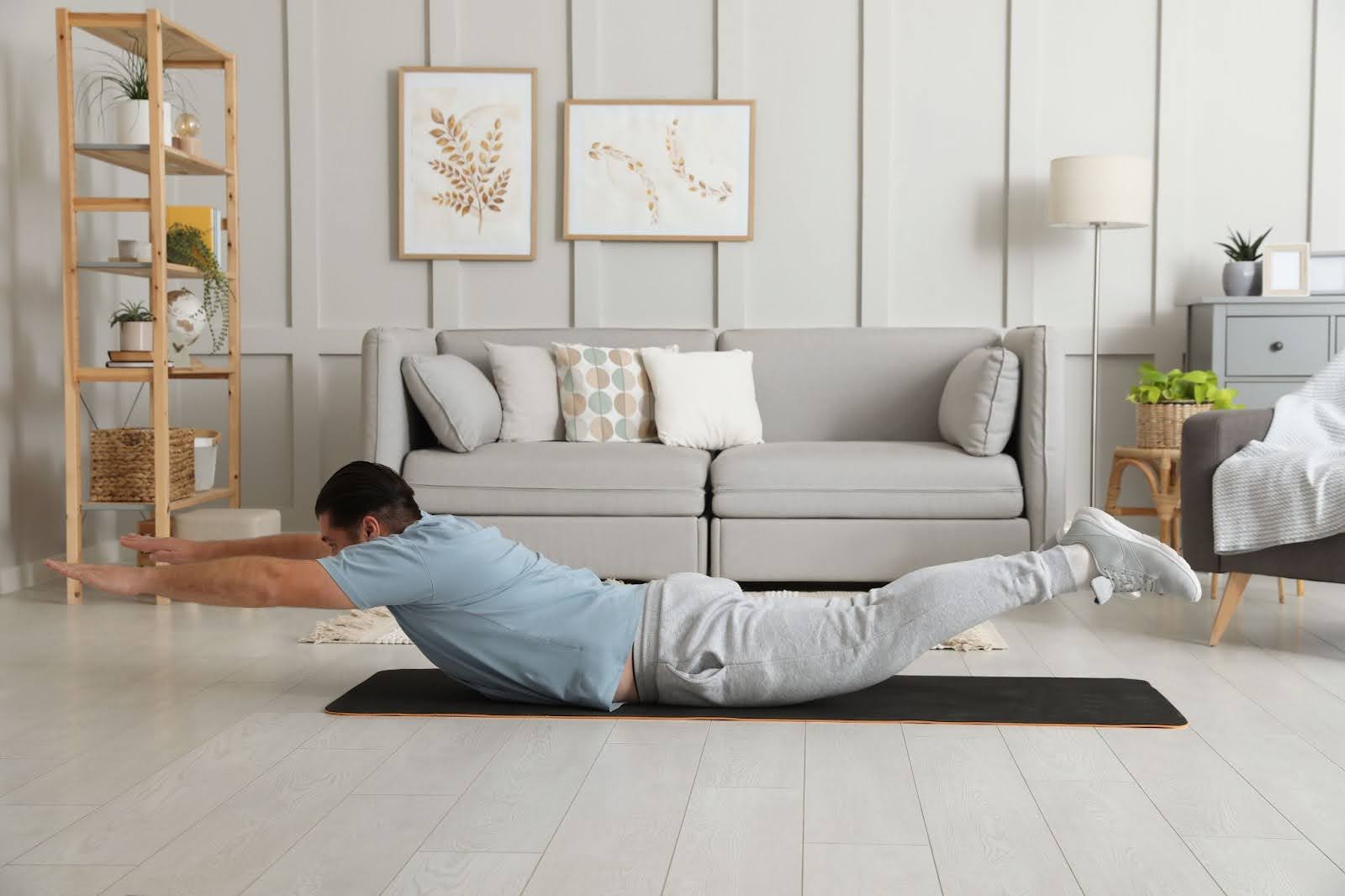 Image of man at home performing superman exercises
