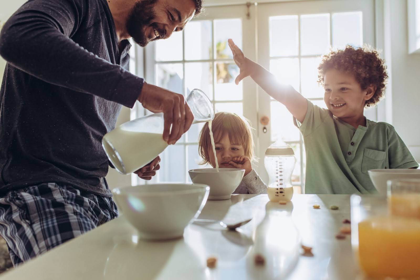 Young family gathered together around the breakfast table having cereal