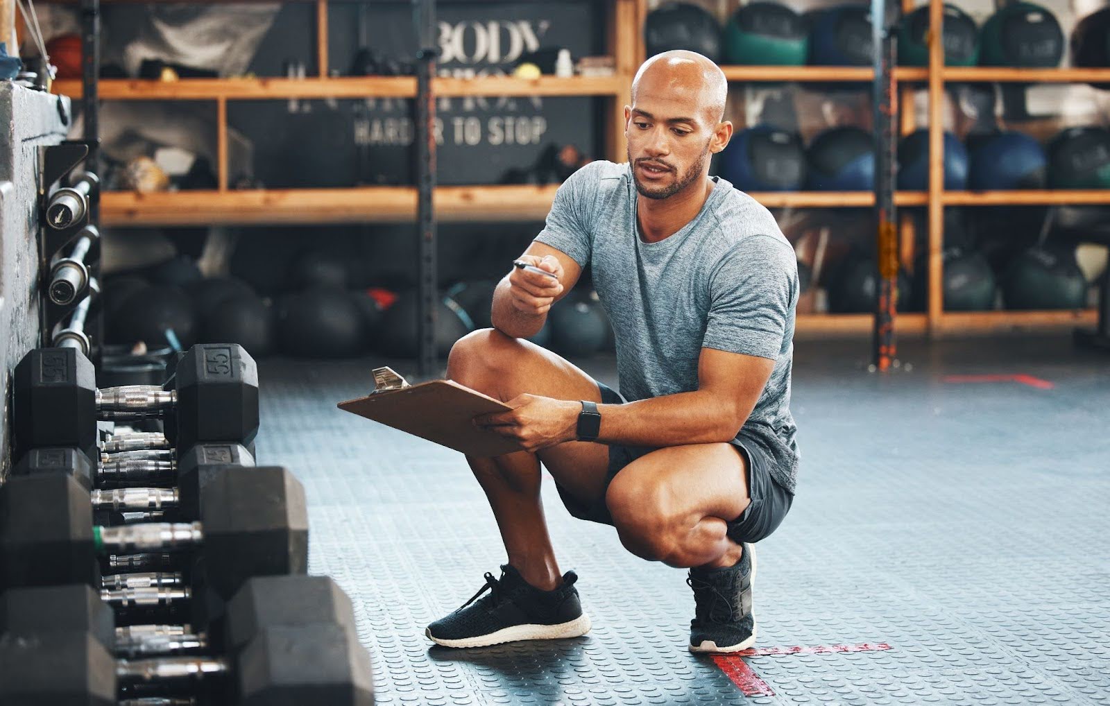 Man squatting, taking notes about his gym progress